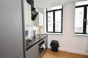 Eine moderne Küche mit schwarzem Arbeitsplatz, Edelstahlgeräten und einer schwarzen Mülltonne.