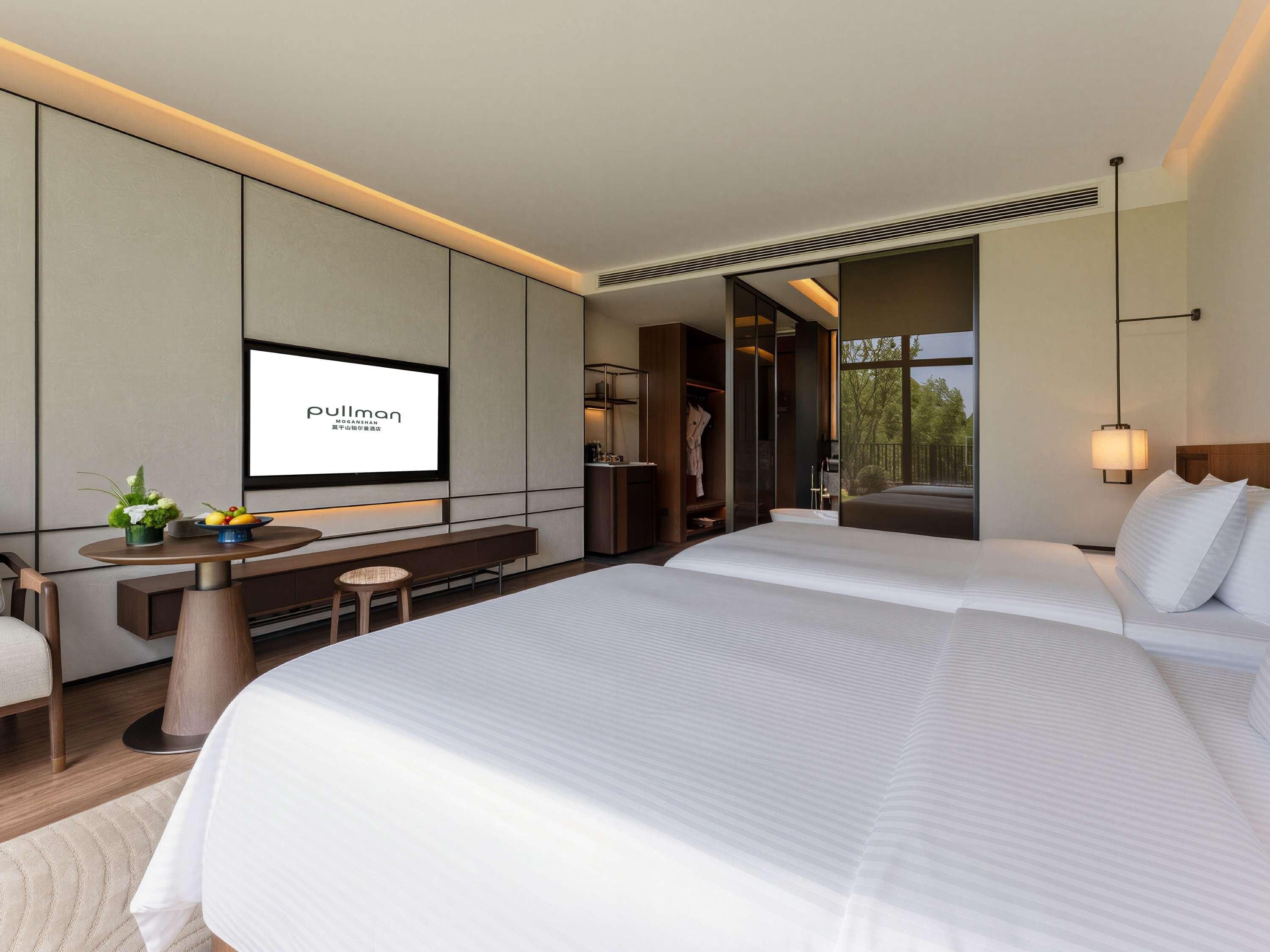 Habitación de hotel moderna con una cama grande, un escritorio con televisor de pantalla plana y vistas al exterior.