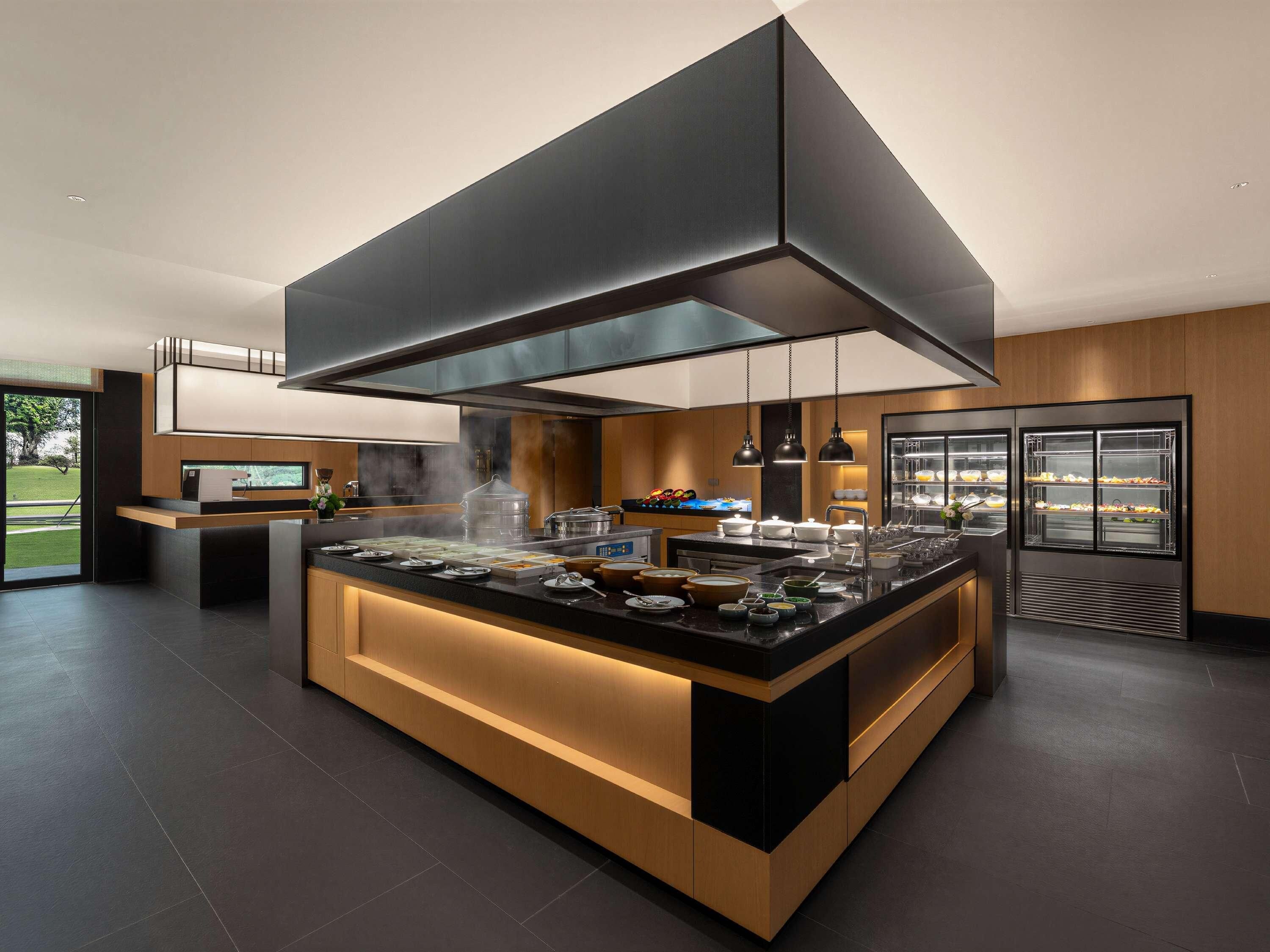 Una cocina moderna con una isla central, electrodomésticos integrados y una campana extractora grande.