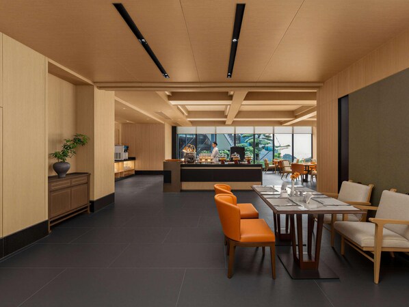 Eine moderne Hotellobby mit einer zentralen Bar, Sitzgelegenheiten und Blick ins Freie.