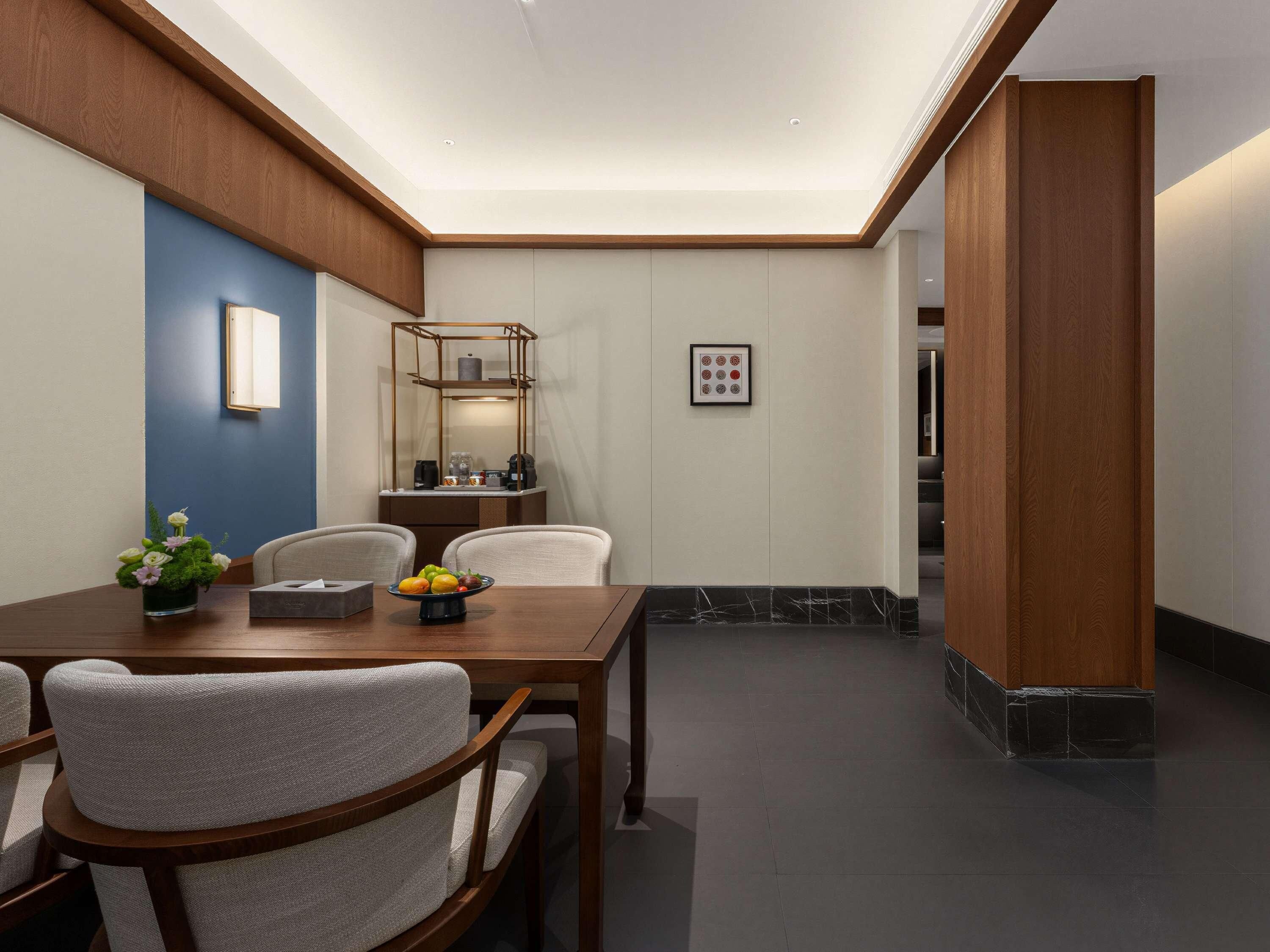 Un comedor moderno con una mesa de madera, sillas acolchadas, un florero y un cuadro en la pared.