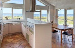 Eine Küche mit Meerblick, ein Essbereich mit Stühlen und ein großes Fenster.