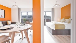 Une chambre d’hôtel moderne dotée d’un coin repas, d’un lit avec vue et d’une grande fenêtre.