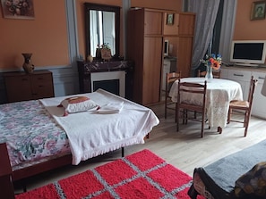 A bedroom with a bed, a desk, a chair, a wardrobe, and a television.
