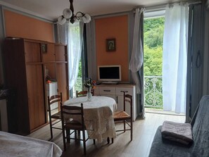 Une piÚce comprenant une table à manger, des chaises, un téléviseur, un canapé et un balcon avec vue.
