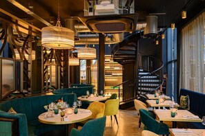 A restaurant interior with round tables, green upholstered seating, hanging pendant lights, and a spiral staircase. - Stay Zeni, Hardwick House Derby Lovely 2 Bed Flat (Derby)