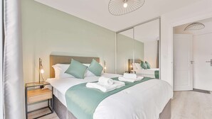 Une chambre d’hôtel avec un lit, des tables de chevet, un miroir et une porte.