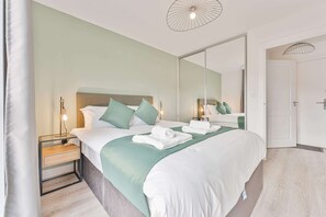 A hotel room with a bed, bedside tables, a mirror, and a door. - Stay Zeni, Hardwick House Derby Lovely 1 Bed Flat (Derby)