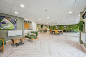A modern interior with a green wall, a wooden coffee table, and a dining area with chairs and a table. - Stay Zeni, Hardwick House Derby Lovely 1 Bed Flat (Derby)