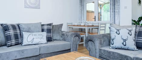 Una sala de estar moderna con sofás grises, una mesa de centro de madera y un comedor con mesa y sillas.