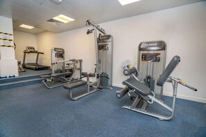Ein Fitnessstudio mit Laufbändern, Kraftgeräten und einer Langhantelbank.