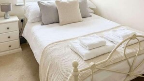 Un dormitorio con cama, mesita de noche, lámpara y ventana con vistas a edificios.