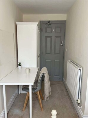 A small, narrow room with a white table, a grey chair, a radiator, and a grey door. - 2 Private Rooms in Shared Apartment with Kitchen (Leeds)