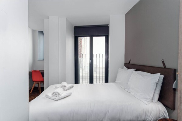 Ein Hotelzimmer mit einem Bett, einem roten Sessel und Blick ins Freie.