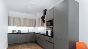 Una cocina moderna con armarios grises, microondas y hervidor.