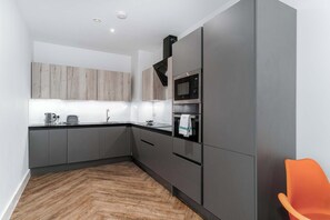 Eine moderne Küche mit grauen Schränken, einer Mikrowelle und einem Wasserkocher.