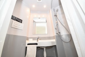 Ein Badezimmer mit Waschbecken, Spiegel, Handtuchhalter und Dusche.