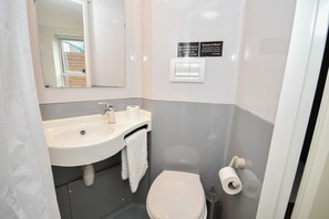 Een badkamer met een wastafel, toilet en spiegel.