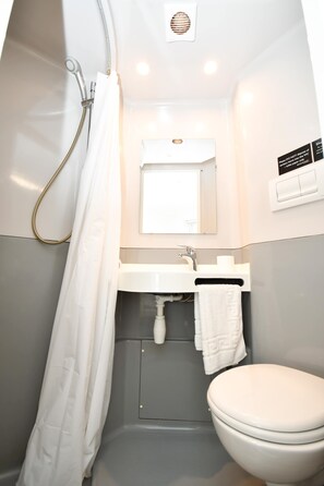 Ein kleines Badezimmer mit Dusche, Waschbecken und Toilette.