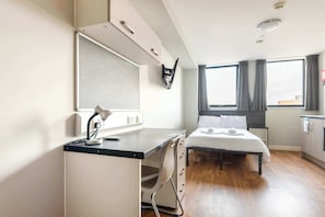 A modern hotel room with a desk, bed, and large windows. - Modern Budget Studio Apartment in Sheffield Centre (Sheffield)