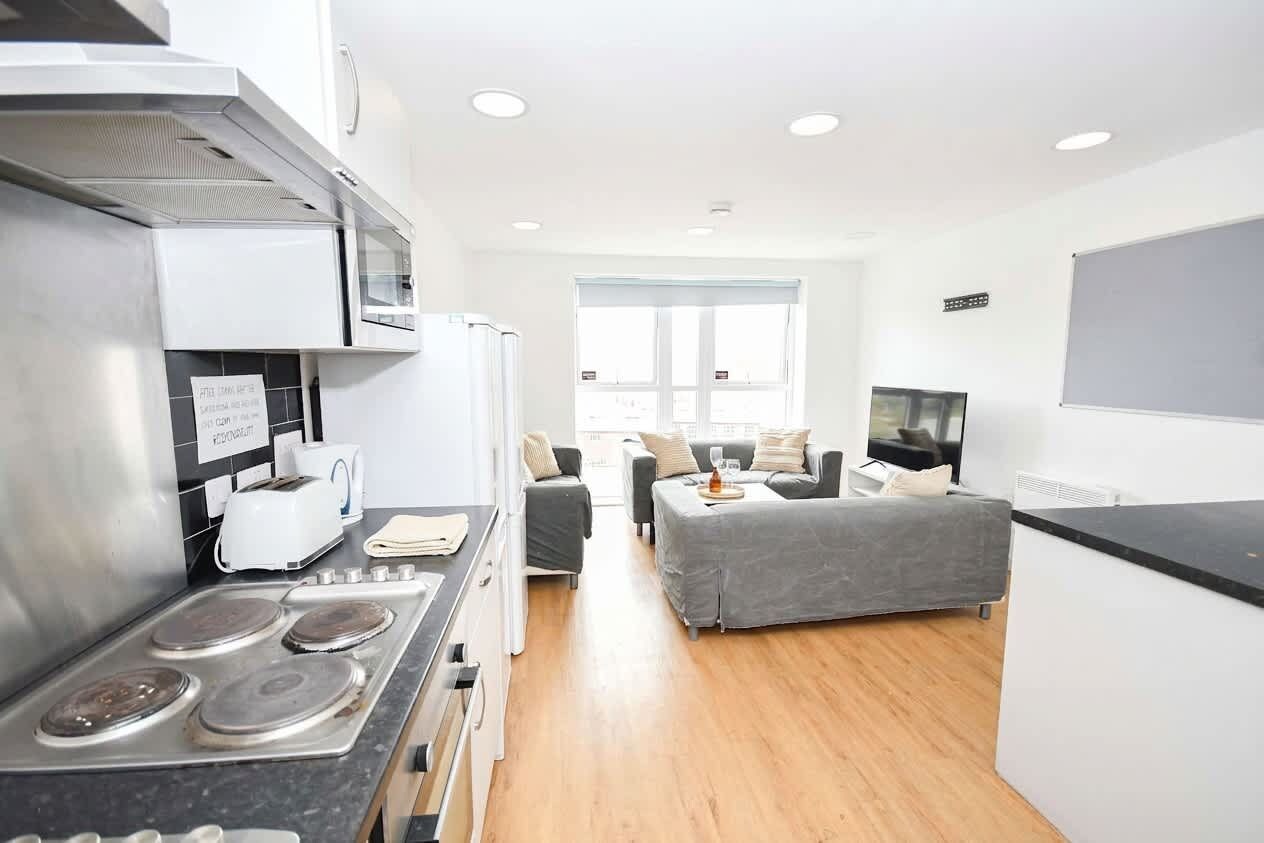 A modern kitchen with a stove, microwave, and a dining area with a sofa and table.