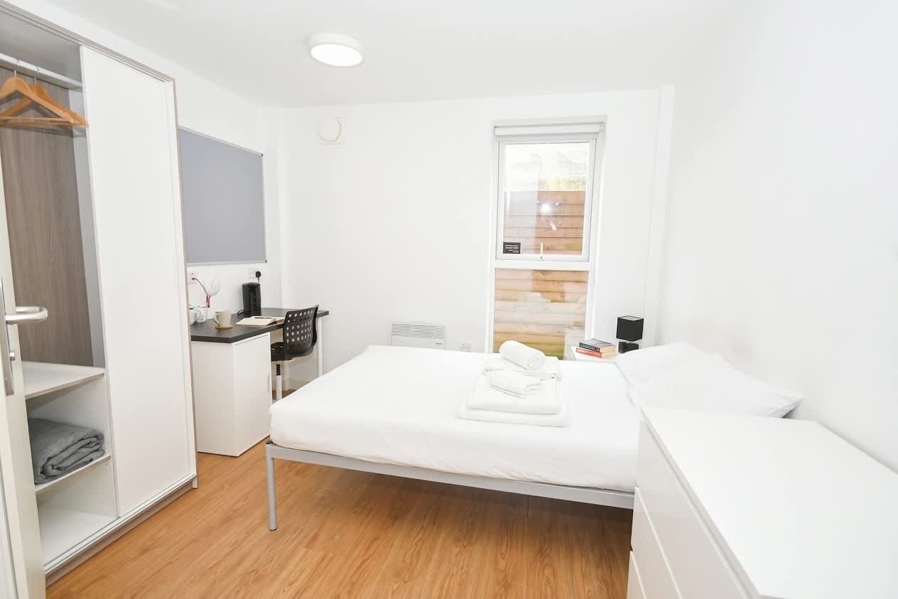 Quarto moderno com cama, escrivaninha e armário.