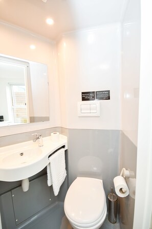 A bathroom with a sink, toilet, and a mirror. There are signs on the wall and a towel hanging on the sink. - Modern & Convenient 4 Bed Apartment in Liverpool (Liverpool)