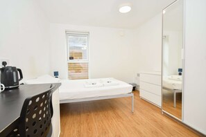 A room with a bed, a desk, a chair, a window, and a mirror. - Convenient 8 Bedroom Apartment in Liverpool (Liverpool)