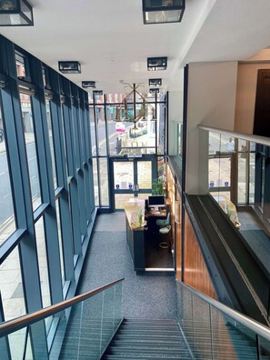 A modern interior with a staircase, a reception desk, and large windows offering views of the street. - Contemporary Studio in Central Hastings Near Beach (East Sussex)