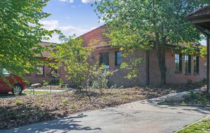 A brick building with a red car parked in front, surrounded by trees and a paved driveway. - 1 bedroom amazing apartment in Ribnitz-Damgarten (Ribnitz-Damgarten)