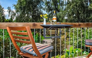 A wooden deck with a metal table, a chair with striped cushions, and a bottle of wine. - 1 bedroom amazing apartment in Ribnitz-Damgarten (Ribnitz-Damgarten)