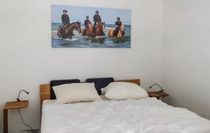 A bedroom with a bed, two bedside tables, and a wall-mounted painting of horses. - Pet friendly apartment in Barth with WiFi (Barth)