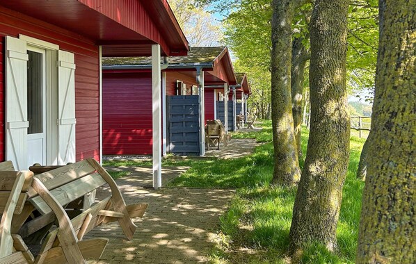 A row of red cabins with wooden benches and a wooden cart on a brick pathway. - Pet friendly apartment in Barth with WiFi (Barth)