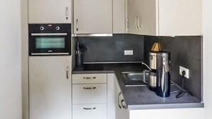Een praktische keuken met een inbouwoven, koffiezetapparaat en een spoelbak.
