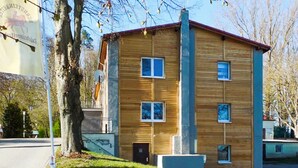 Een gebouw met twee verdiepingen, een houten gevel, meerdere ramen en een rood dak.