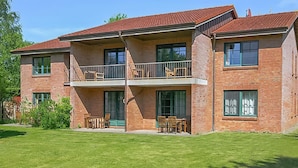 A two-story brick building with a balcony on the second floor, large windows, and a well-maintained lawn. - Cozy apartment in Ribnitz-Damgarten with house a panoramic view (Ribnitz-Damgarten)
