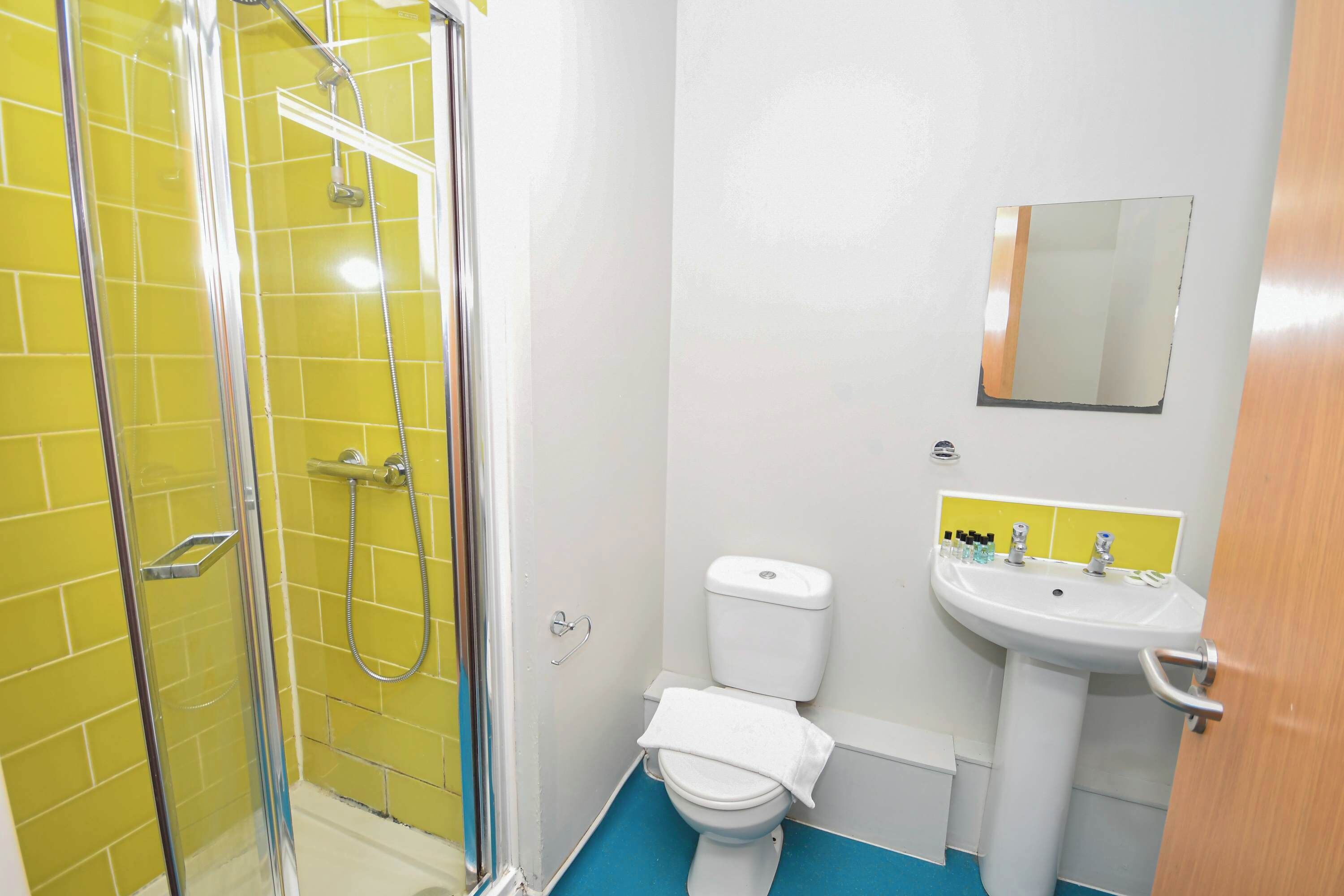 A bathroom with a shower, toilet, sink, and mirror.