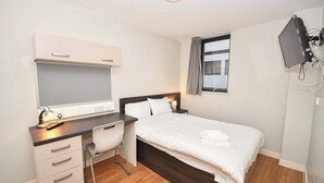 A bedroom with a bed, desk, chair, and a TV mounted on the wall. - Spacious Budget 3-Bed Sheffield Centre Apt (Sheffield)