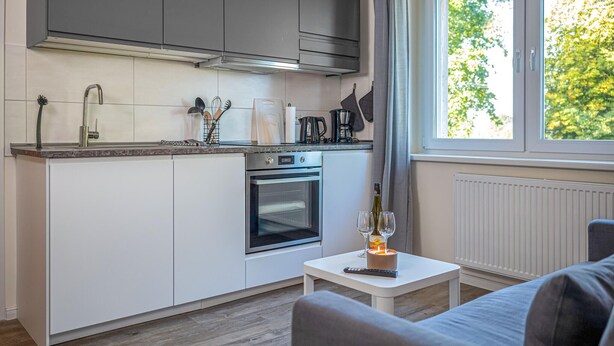 Una cucina compatta con forno integrato, una macchina per il caffè e una finestra vista alberi.