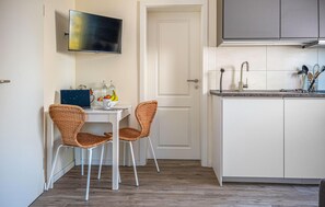 A compact kitchen with a dining area, a TV mounted above the table, and a door leading to another room. - 1 bedroom amazing apartment in Barth (Barth)