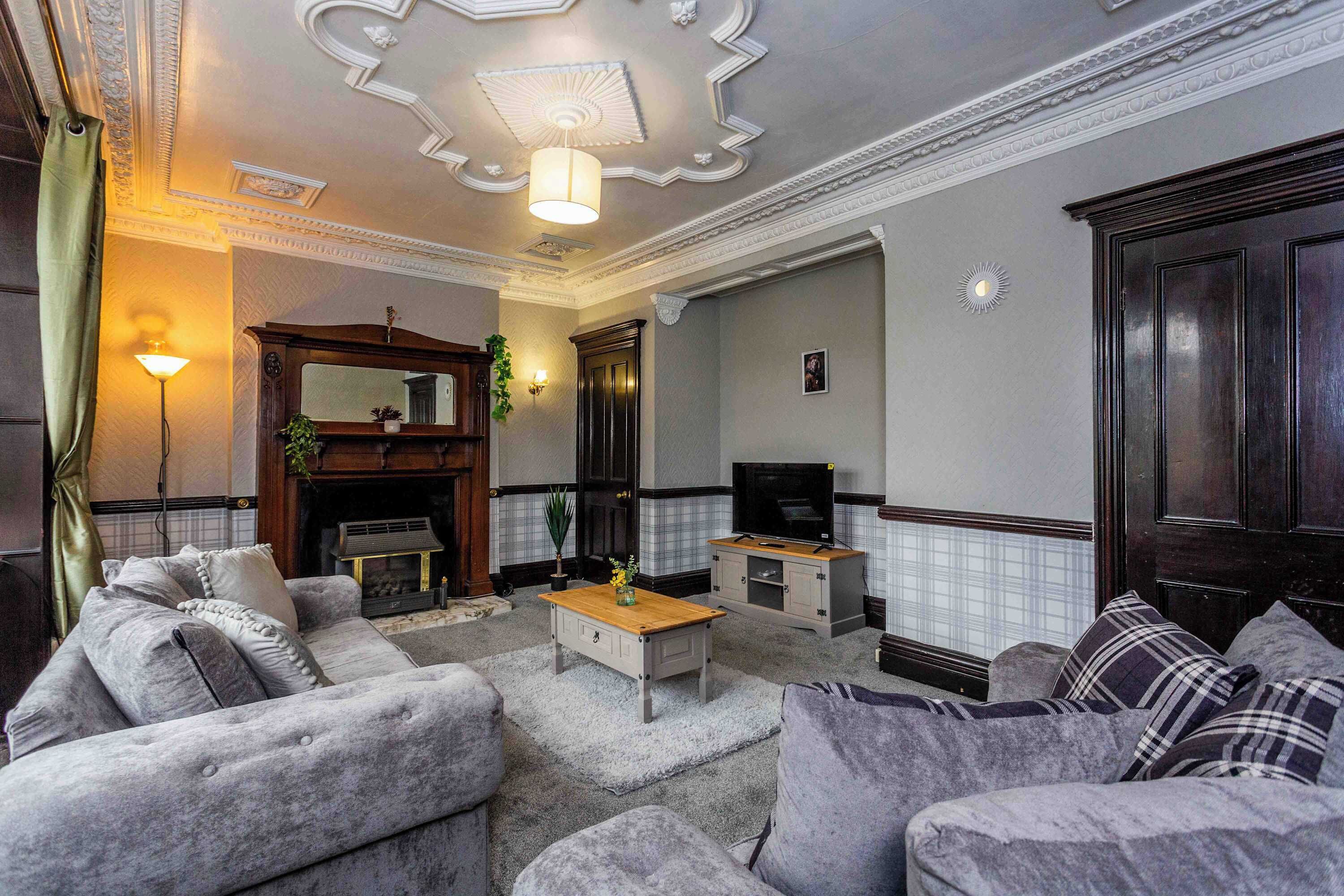 A living room with a fireplace, sofa, television, and decorative elements.
