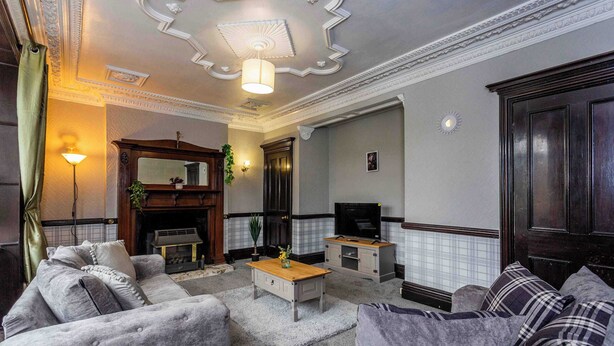A living room with a fireplace, sofa, television, and decorative elements. - Sunny, Spacious 3-Bedroom Getaway in Haltwhistle (Haltwhistle)