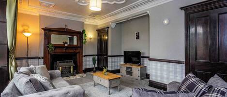 Una sala de estar con chimenea, sofá, televisor y detalles decorativos.