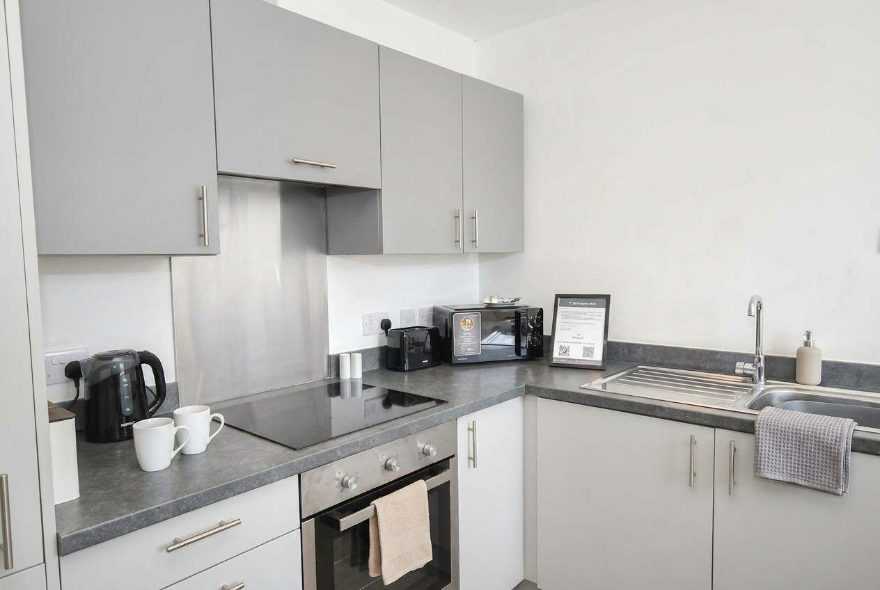 Eine moderne Küche mit grauen Schränken, einem eingebauten Backofen, einer Mikrowelle und einer Kaffeemaschine.