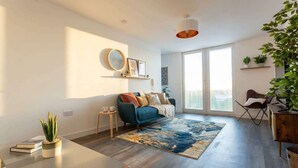 A modern living room with a sofa, coffee table, and a large window. - Modern & Spacious 2BED Apartment by Old Trafford (Manchester)