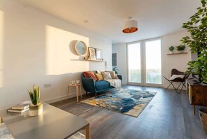 A modern living room with a sofa, coffee table, and a large window. - Modern & Spacious 2BED Apartment by Old Trafford (Manchester)