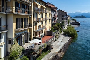Ein Hotel am Wasserufer mit Balkonen, einem Steinweg und Seeblick.