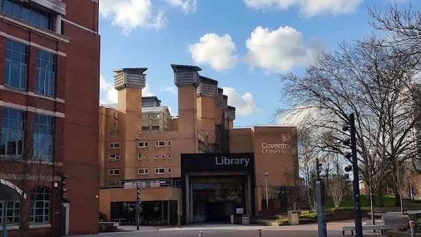 Ein Bibliotheksgebäude mit moderner Architektur, das einen markanten Eingang und einen klaren Himmel zeigt.