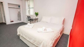 Ein Hotelzimmer mit Bett, Schreibtisch, Stuhl, Fenster und Pflanze.