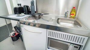 Una piccola cucina compatta con fornello, lavello e un mini-frigorifero.